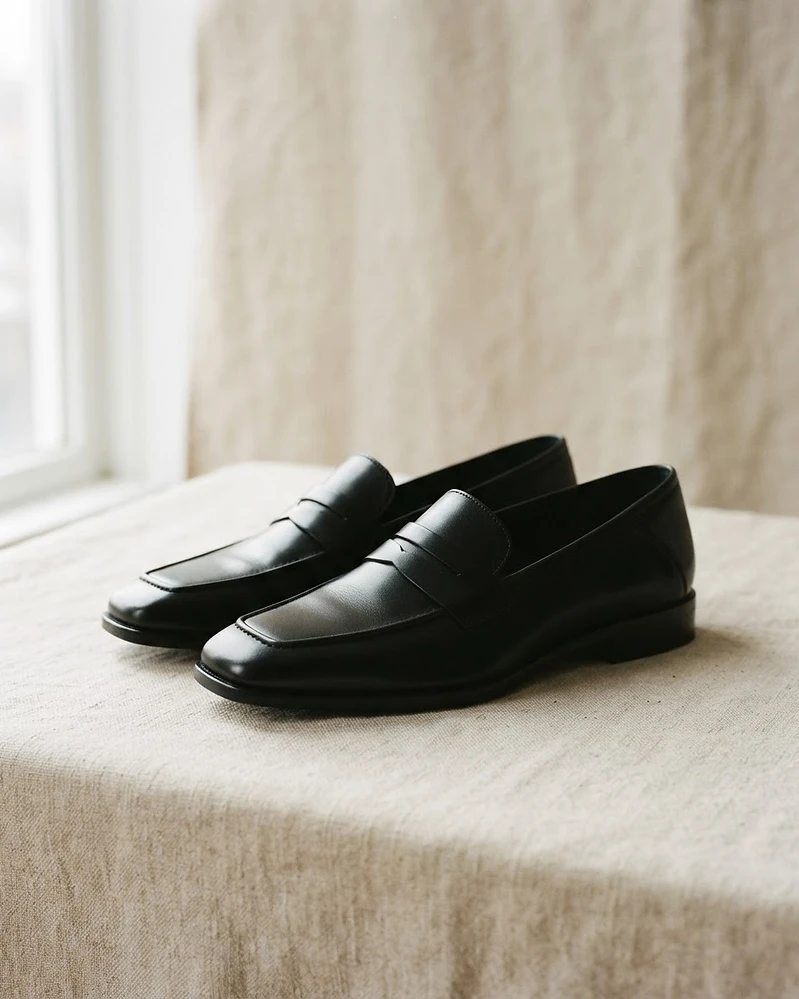 Black leather square-toe loafers on linen